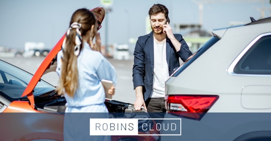 a man and a woman on the phone outside of the scene of a car accident.